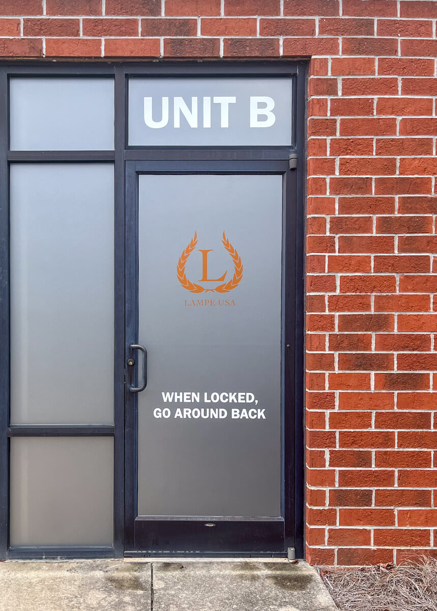 A storefront with clean, professional window graphics showing logos and business hours.